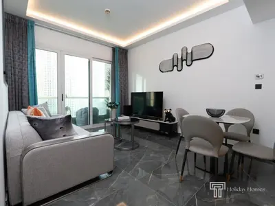 a living room with a couch and chairs and a tv at Cozy and Uniquely Furnished One Bedroom Dubai Marina in Dubai