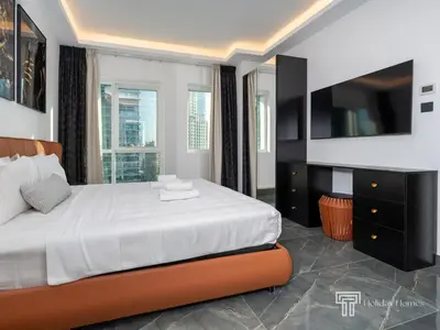 a bedroom with a large bed and a tv at Cozy and Uniquely Furnished One Bedroom Dubai Marina in Dubai