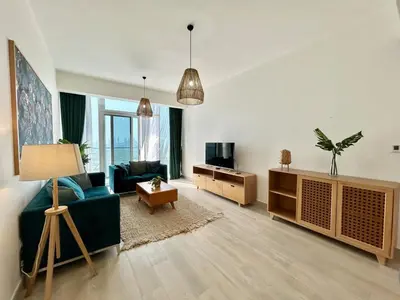 a living room with a blue couch and a tv at Homes2Retreat - Luxury Finishes with Full Skyline View in Dubai
