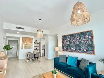 a living room with a blue couch and a dining room at Homes2Retreat - Luxury Finishes with Full Skyline View in Dubai