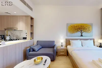 a hotel room with a bed and a chair and a table at Brand New and Modern Studio Apartment in Dubai