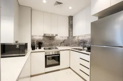 a kitchen with white cabinets and a stainless steel refrigerator at Centrally Located 1BR in Business Bay Near Canal and Downtown in Dubai