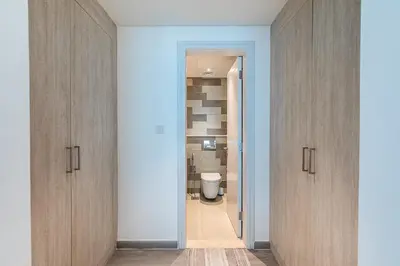 a bathroom with wooden cabinets and a toilet at Bright & Elegant Saven The Palm 1bhk Apartment in Dubai