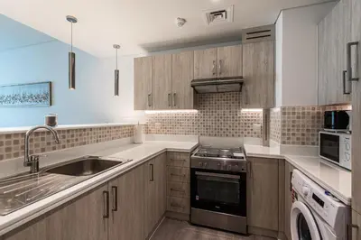 a kitchen with a sink and a stove top oven at Bright & Elegant Saven The Palm 1bhk Apartment in Dubai