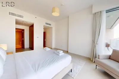 a white bedroom with a bed and a couch at Elegant 2BR with Maids and Stunning Canal Views in Dubai