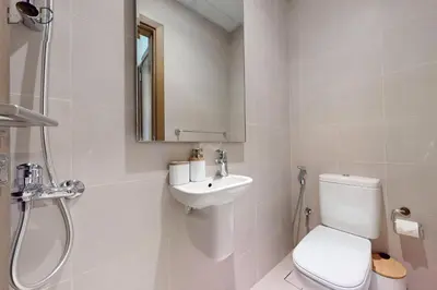 a white bathroom with a toilet and a sink at Elegant 2BR with Maids and Stunning Canal Views in Dubai
