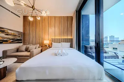a bedroom with a large bed and a living room at Hamilton House, Jumeirah Village Circle in Dubai