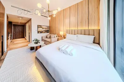 a bedroom with a large bed and a living room at Hamilton House, Jumeirah Village Circle in Dubai