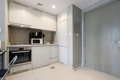 a kitchen with white cabinets and a microwave at Stylish 1BR Close to Metro Burj Khalifa & Dubai Canal in Dubai