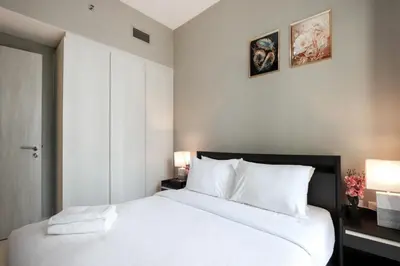 a bedroom with a large white bed with two lamps at Stylish 1BR Close to Metro Burj Khalifa & Dubai Canal in Dubai