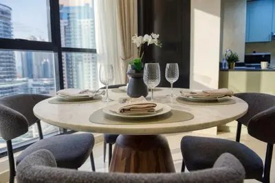 a dining room table with chairs and a table with glasses at Elegant Cozy Marina Home in Dubai