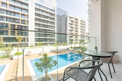 an apartment balcony with a pool and a table and chairs at Pool and Community View Studio, Near Top Landmarks, Azizi Riviera 59, Al Merkadh by Deluxe Holiday Homes in Dubai