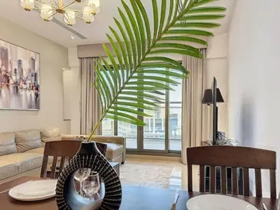 a living room with a table and a palm plant at Stylish 1BR in Downtown Dubai in Dubai