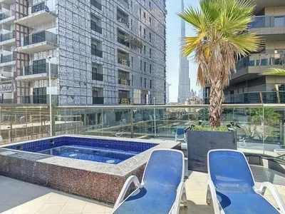 a hot tub on a balcony with chairs and a palm tree at Stylish 1BR in Downtown Dubai in Dubai