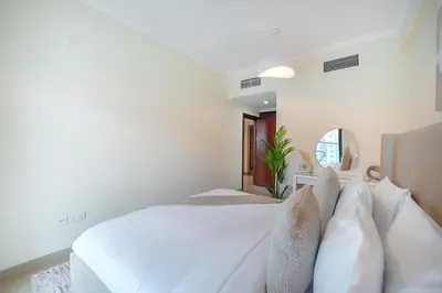 a white bedroom with a large bed and a mirror at EasyGo-Marina Living with View and Amenities in Dubai