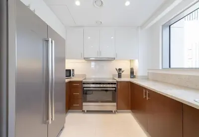 a kitchen with wooden cabinets and a stainless steel refrigerator at Luxury 3BR Downtown Stay Near Burj in Dubai