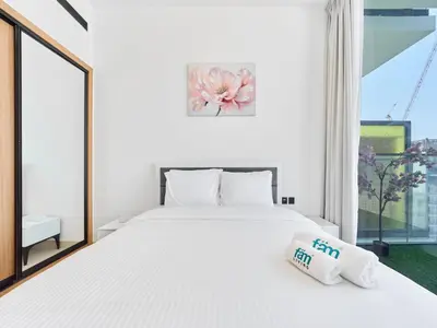 a bedroom with a large white bed and a window at FAM Living Minimalist 1BR Gem in Binghatti Amber in Dubai