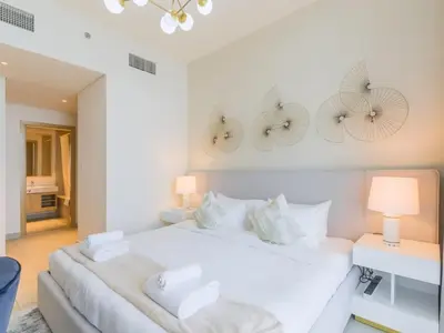 a white bedroom with two clocks on the wall at TRPS - Creek Rise Tower, Dubai Creek Harbour - 3BR with Marina View in Dubai