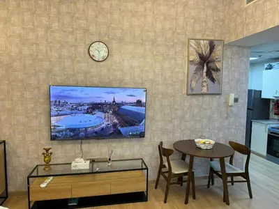 a living room with a table and a clock on a wall at Champion Tower 1 Sports city By Al sarya Holiday Homes in Dubai