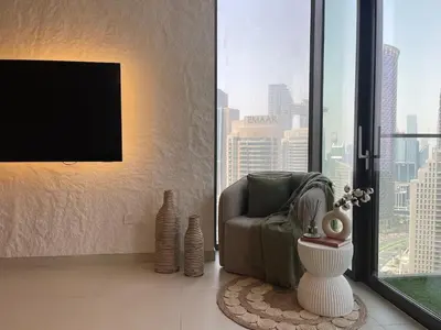 a living room with a tv and a chair and a window at Prestige stay next to Burj Khalifa in Dubai