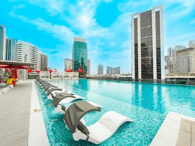 a pool with chaise lounge chairs on the roof of a building at Luxury Escapes Modern Studio MAG 318 in Dubai