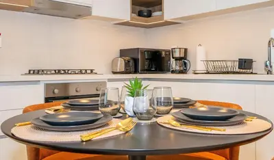 a table with plates and glasses on it in a kitchen at Zapbed House -Stylish 1 BR Apartment Downtown Views II Tower 2 in Dubai