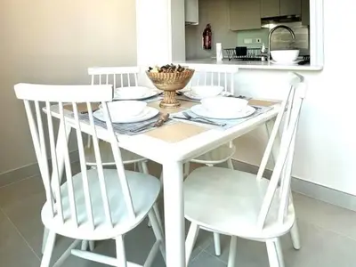 a white dining room table with two white chairs at Cozy 1BR in Burj Views I Top Location Walk to Dubai Mall & Burj Khalifa I Wi-Fi in Dubai