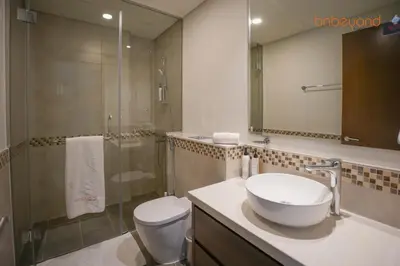 a bathroom with a sink and a toilet and a shower at Bnbeyond's Canal Dreams and Luxe 2BR in Dubai
