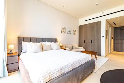 a bedroom with a large bed and a chair at SuperHost- Modern Studio in Arjan with pool & Gym in Dubai