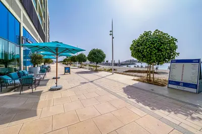 a patio with tables and chairs and a blue umbrella at Sea View 2BR Apartment in Beach Vista 2 in Dubai
