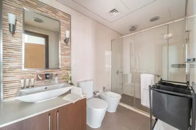 a bathroom with a sink and a toilet and a mirror at Lavish 2BR - Study with Spacious Balcony in DIFC in Dubai