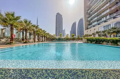 a large swimming pool with palm trees and buildings at Lavish 2BR - Study with Spacious Balcony in DIFC in Dubai