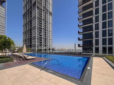 a swimming pool in the middle of two tall buildings at Frank Porter - Creek Crescent Tower 1 in Dubai