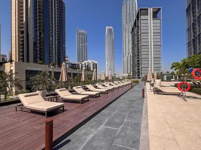 a row of lounge chairs and umbrellas on a deck with buildings at Frank Porter - Creek Crescent Tower 1 in Dubai