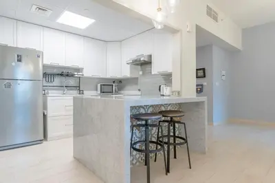 a kitchen with white cabinets and a counter with stools at Seashell stunning 2 bedrooms in JBR in Dubai