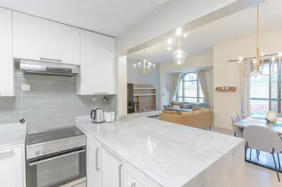 a kitchen with white cabinets and a dining room at Seashell stunning 2 bedrooms in JBR in Dubai