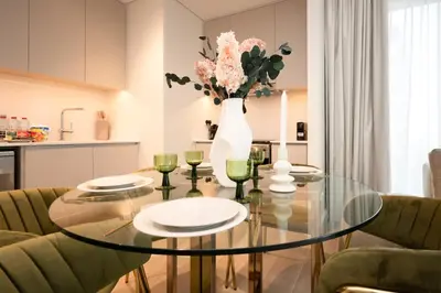 a dining room with a glass table and a vase with flowers at Creek New Luxury Stay Beach and Lagoona Access in Dubai