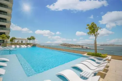 a swimming pool with lounge chairs and the ocean at Vacationer I Luxurious 1 Bedroom Apartment I Private Beach and Infinity Pool Access in Dubai