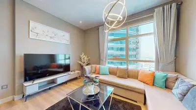 a living room with a couch and a large window at Vacationer I Steps to Metro I Premium 2 Bedroom Apartment I Yacht Bay Marina in Dubai