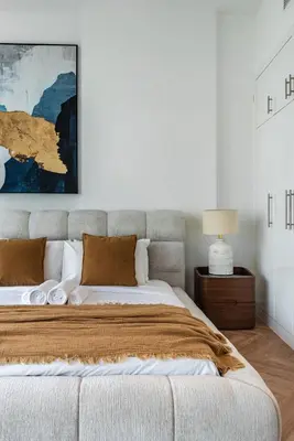 a white bedroom with a large bed and a lamp at Vibrant Waterfront Duplex in Dubai Marina in Dubai