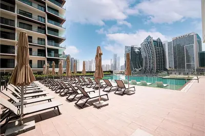 a row of lounge chairs and umbrellas next to a pool at Luxury Apartment Burj Khalifa View Summer Offer in Dubai