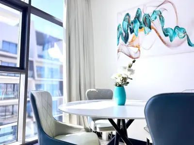 a table with chairs and a vase of flowers on it at Luxury Apartment Burj Khalifa View Summer Offer in Dubai