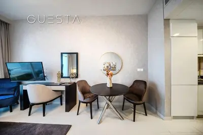 a dining room with a table and chairs and a tv at Damac Hills - Artecia Tower, Dubai in Dubai