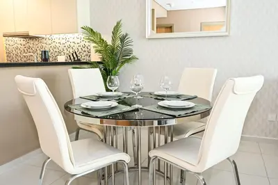 a dining room with a glass table and white chairs at Amazing 2 Bed Burj views in Dubai