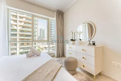 a white bedroom with a large window and a white dresser at 2BR with Marina View, Walking Distance to Marina Mall, Metro Station & JBR Beach, Al Majara 1, Dubai Marina by Deluxe Holiday Homes in Dubai