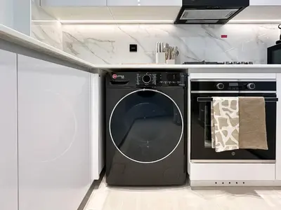 a black washer and dryer in a white kitchen at Feel at Home Stylish 1BR in Binghatti Tulip Dubai in Dubai