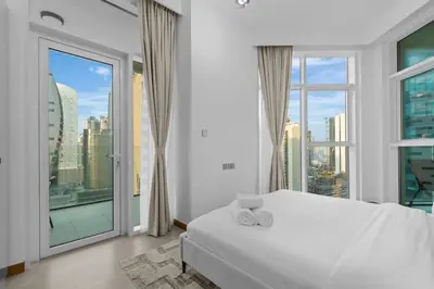 a bedroom with a white bed and a large window at Modern apartment in a prime location in Dubai! in Dubai