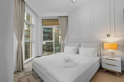 a white bedroom with a large bed and a window at Modern apartment in a prime location in Dubai! in Dubai