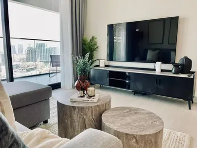 a living room with a large television and two tables at Modern 1br In Jvc Balcony Pool Free Parking in Dubai