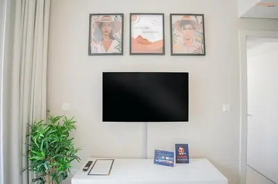 a flat screen tv hanging on a white wall at Bnbeyond's Serene Poolside Bliss in Dubai